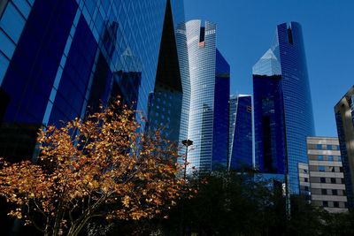 Low angle view of modern skyscraper against blue sky