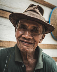 Close-up portrait of senior man wearing sun hat by wall