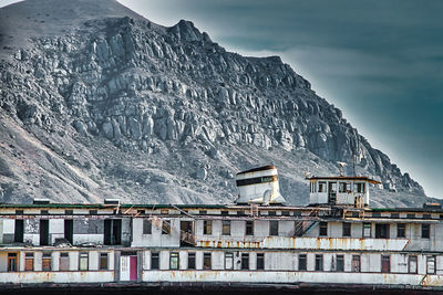 Buildings by mountain against sky during winter