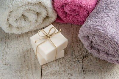 High angle view of soap bars with rolled up towels on wooden table