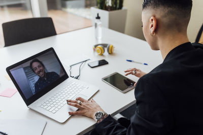 Female entrepreneur using digital tablet during video call through laptop at office