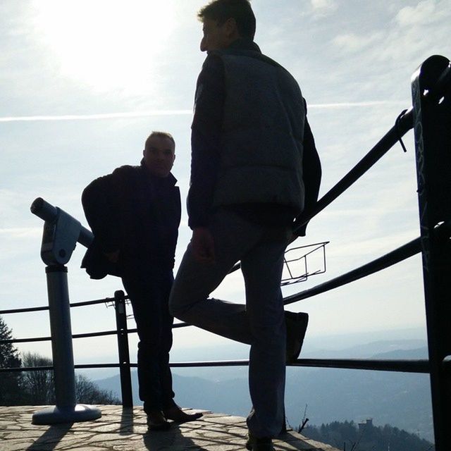 MEN STANDING ON SHORE AGAINST SKY