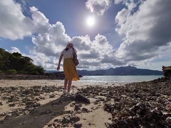 Rear view of man standing at beach against sky