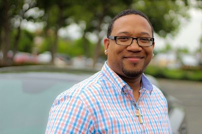 Portrait of young man wearing eyeglasses while standing against trees at park