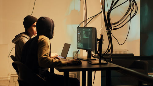 Rear view of man using laptop at office