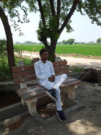 Man sitting on bench against trees