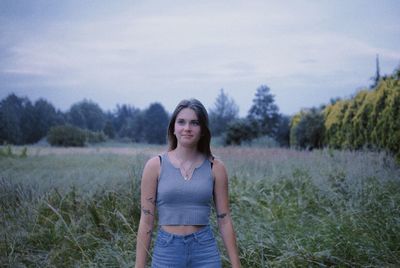 Portrait of young woman standing against sky