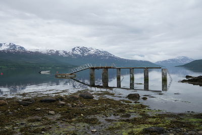 Bridge over lake by mountain against sky