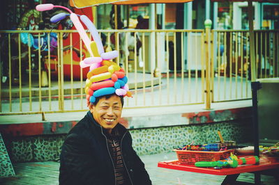 Happy man wearing balloon hat in amusement park