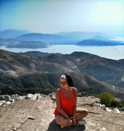 Young woman standing on mountain against sky