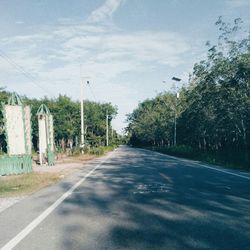 Empty road amidst trees against sky