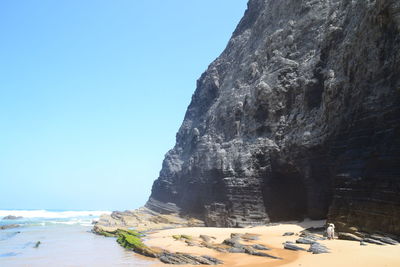 Rock formations by sea against clear blue sky