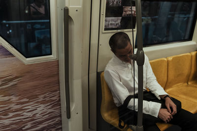 Man with bag sleeping while sitting in train