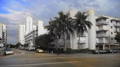 Road by buildings in city against sky