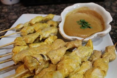 High angle view of chicken skewers served with peanut sauce in plate