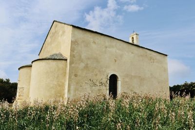 Low angle view of old building on field against sky