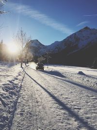 Snow covered road by mountains against sky