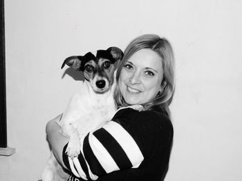 Portrait of smiling woman holding puppy against white background