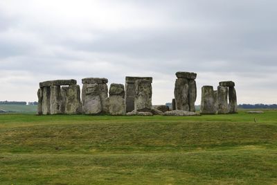 Old ruins on field against cloudy sky