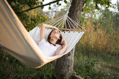 Young woman relaxing on hammock at park