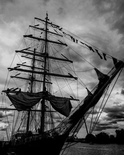 Low angle view of sailboat sailing in sea against cloudy sky