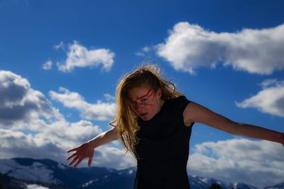 Portrait of woman with painted face standing against mountains and sky