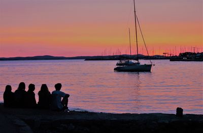 Silhouette people in boat against sea during sunset