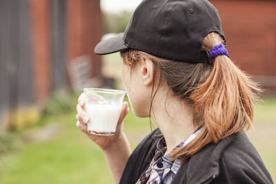 Side view of woman drinking milk at farm