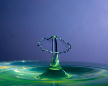 Close-up of water drop against colored background