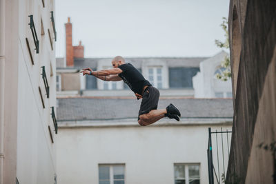 Low angle view of man jumping against buildings