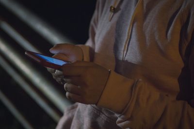 Midsection of woman using mobile phone at night