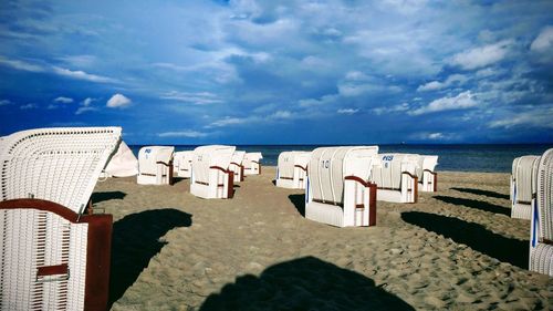 Hooded chairs on beach against sky