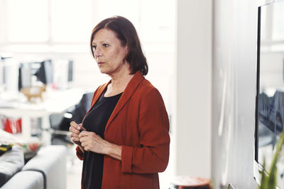 Side view of mature businesswoman giving presentation in front of television