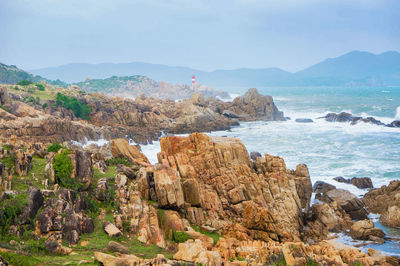 Scenic view of rocky shore and sea against sky