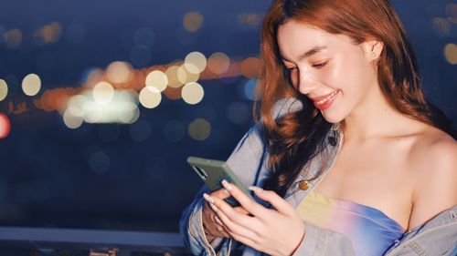 Young woman using mobile phone at music concert
