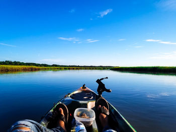 Man on boat in lake against blue sky