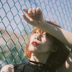 Close-up portrait of girl seen through chainlink fence