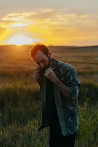 Man standing on field against sky during sunset