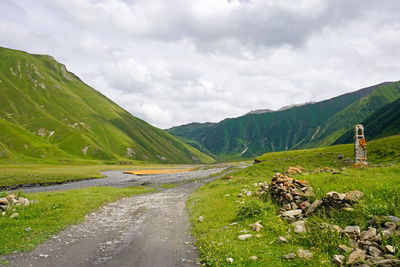 Road amidst green landscape against sky