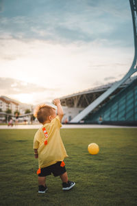 Boy playing with ball in background at sunset