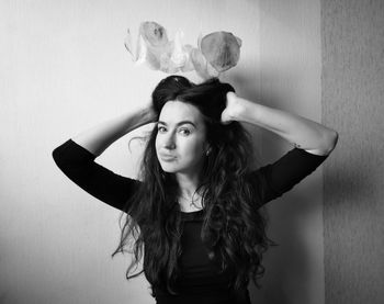 Portrait of young woman standing against wall