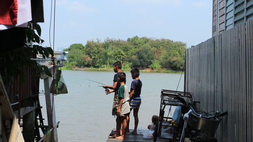 Rear view of people on shore against sky