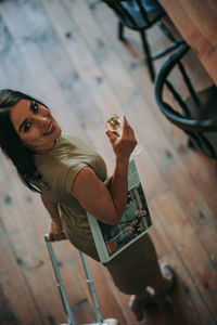 Portrait of young woman sitting on wooden floor