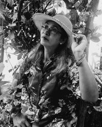 Portrait of young woman wearing hat against trees