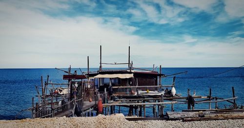 Deck chairs by sea against sky