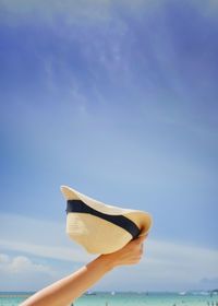 Low section of person holding blue sea against sky