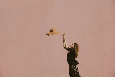 Side view of woman holding bird standing against blurred background