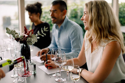 Smiling businesswoman looking away while sitting at table with colleagues in convention center