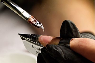 Close-up of hand doing nail art on customer finger