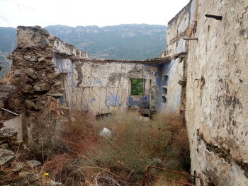 Old building by mountain against sky